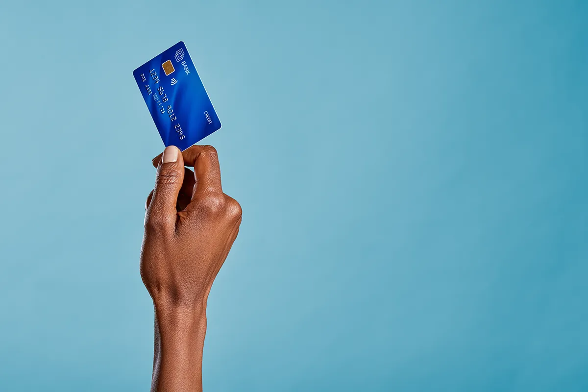 une main qui tient une carte bleu, photo en studio sur fond bleu