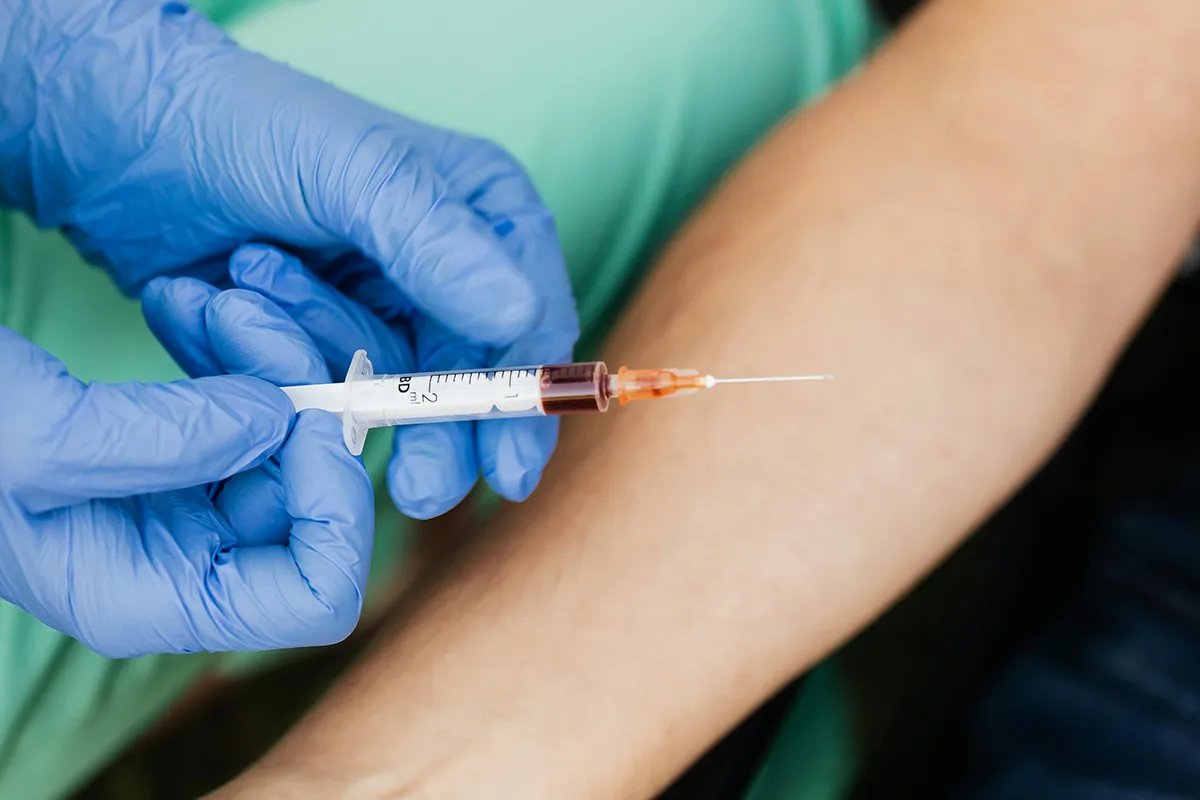 Prise de sang réalisée par un soignant avec gants médicaux